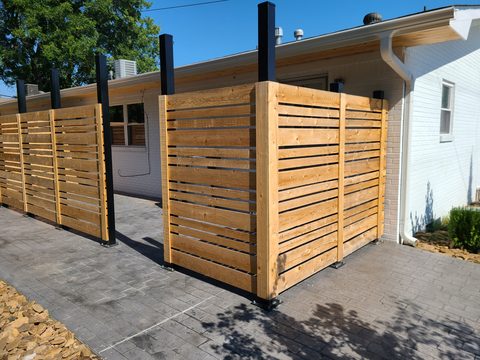 Modern horizontal-slat cedar privacy screens with steel posts on a stamped-concrete patio in Northwest Arkansas