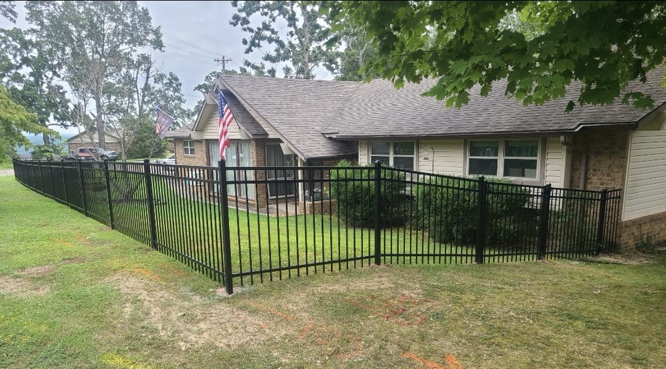 Black powder-coated aluminum fence framing the front yard of a brick home in Northwest Arkansas