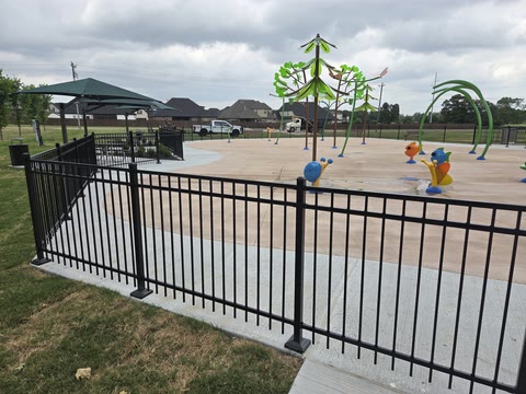 Black aluminum fence enclosing a community splash pad in Northwest Arkansas