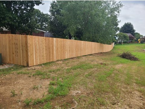 Cedar privacy fence stepping cleanly down a sloped Northwest Arkansas yard